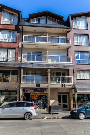 A multi-story building with balconies, a pharmacy, and a rental service.