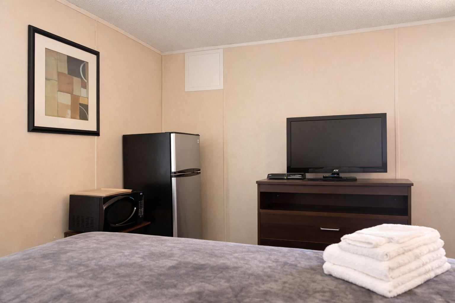 Una habitación de hotel con una cama, televisión, refrigerador y microondas.