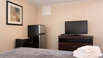 Una habitación de hotel con una cama, televisión, refrigerador y microondas.