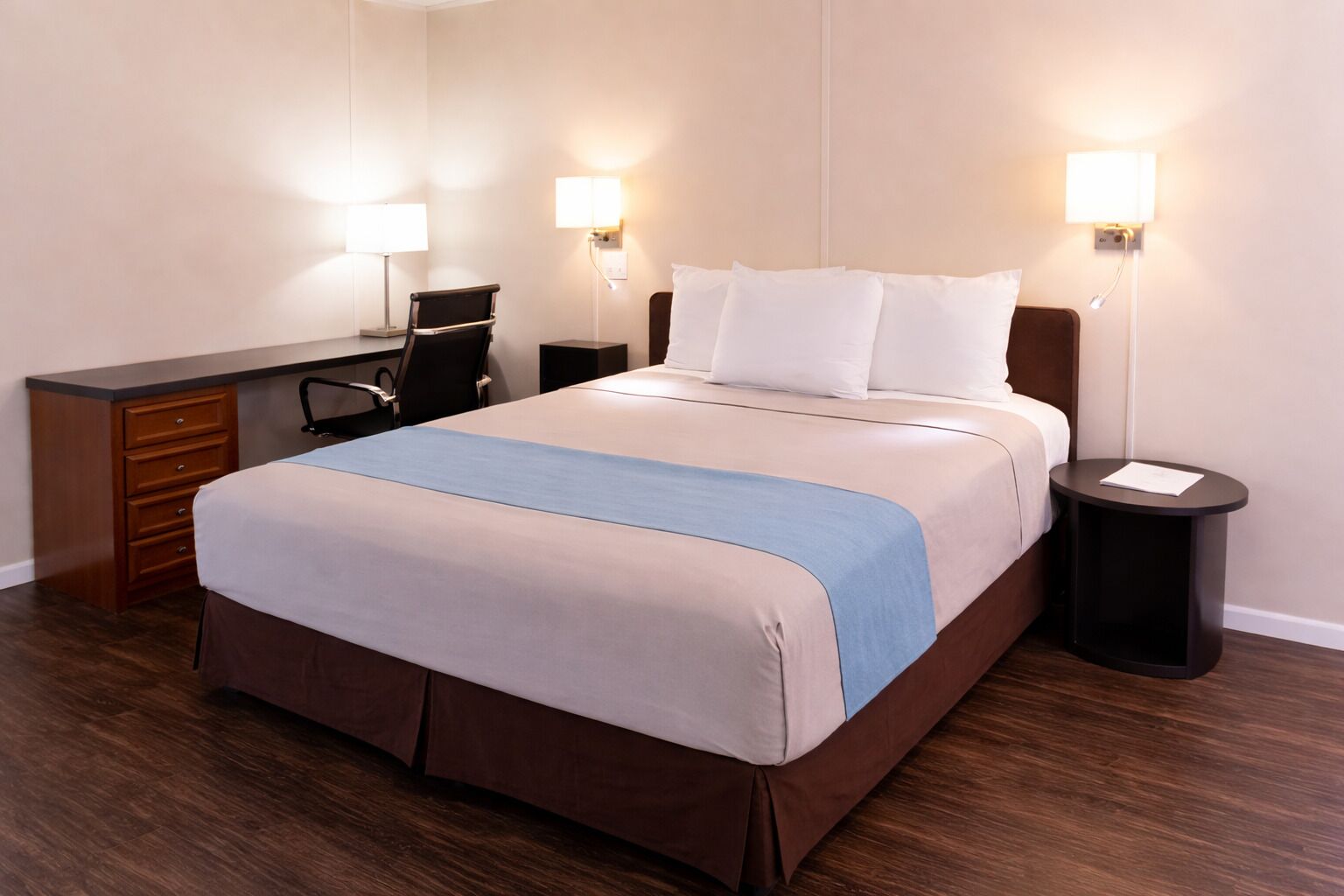 Una habitación de hotel con cama, escritorio, silla y dos mesitas de noche.