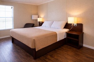 A hotel room with a bed, two bedside lamps, a chair, and a nightstand.
