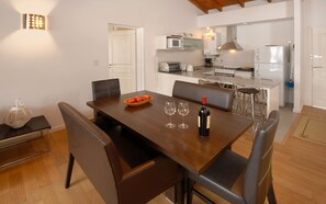 A dining area with a wooden table, chairs, and a bowl of fruit.