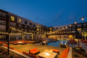 A courtyard with a swimming pool, outdoor seating, and string lights. - BridgeStreet at the Vue (Beachwood)