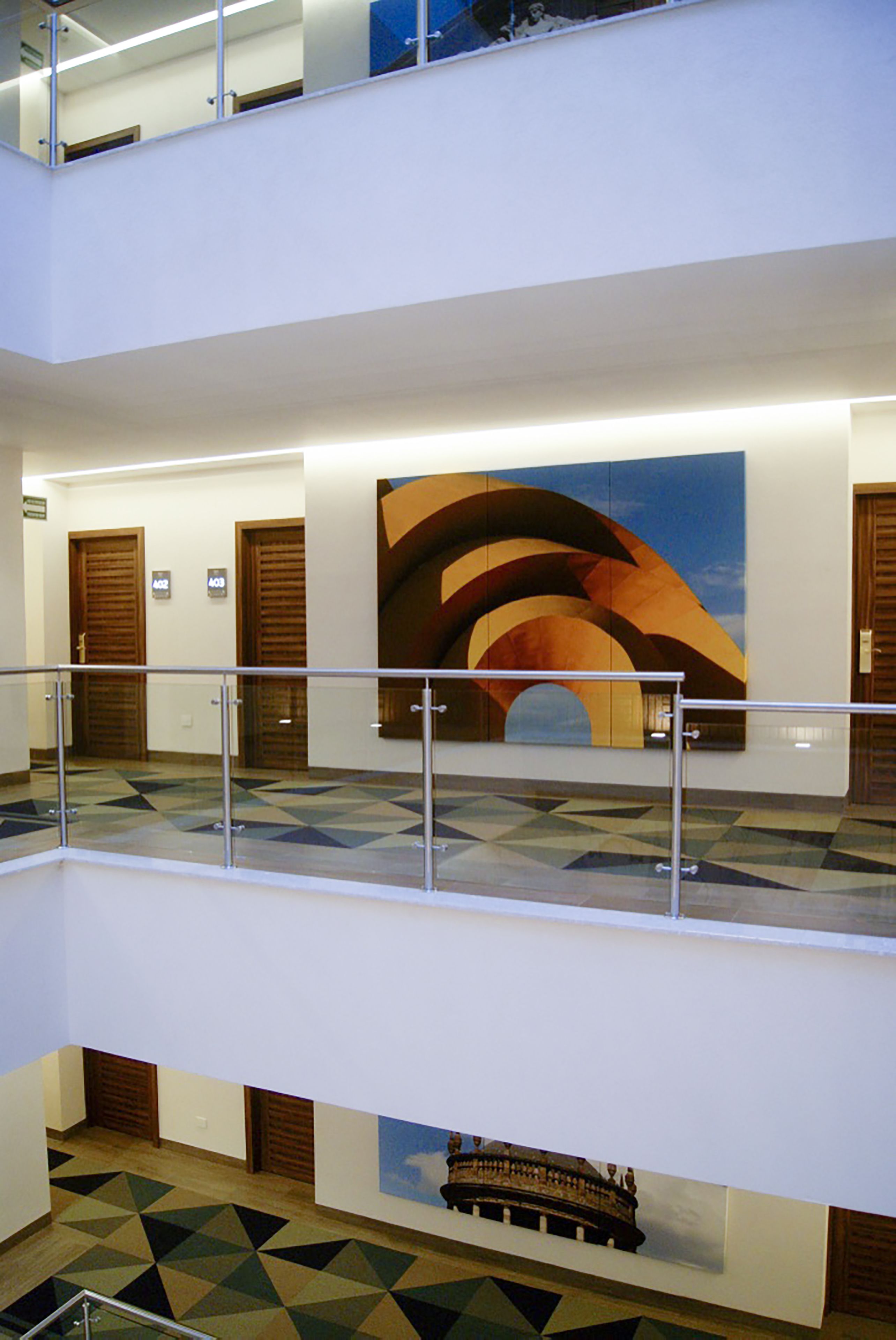 Rebedor d'hotel de diversos nivells, amb un paviment de disseny geomètric, un gran quadre abstracte i una maqueta de tren.