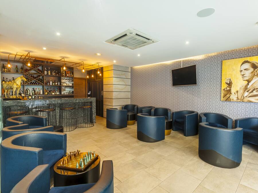 Zona de bar moderna com lugares sentados e uma grande tela de televisão.