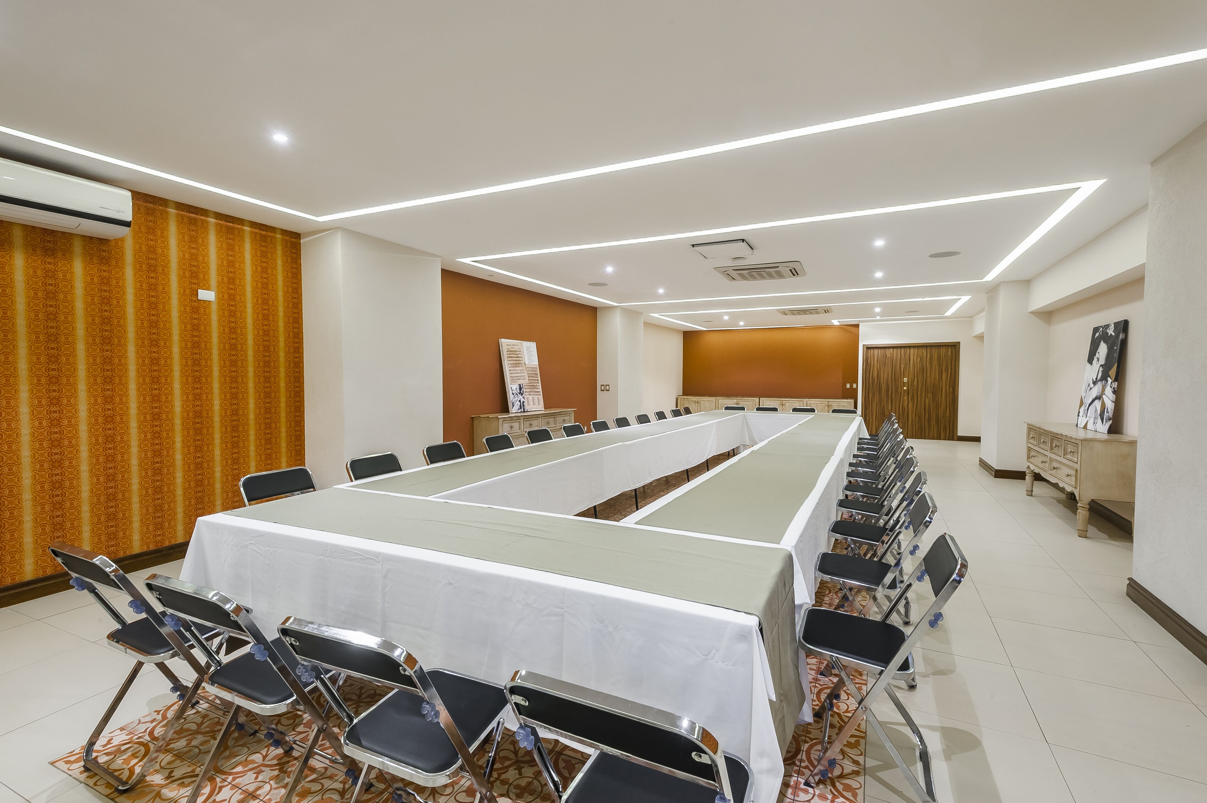 Ein Konferenzraum mit einem langen Tisch, Stühlen und einer weißen Tischdecke.