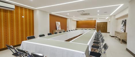 Ein Konferenzraum mit einem langen Tisch, Stühlen und einer weißen Tischdecke.