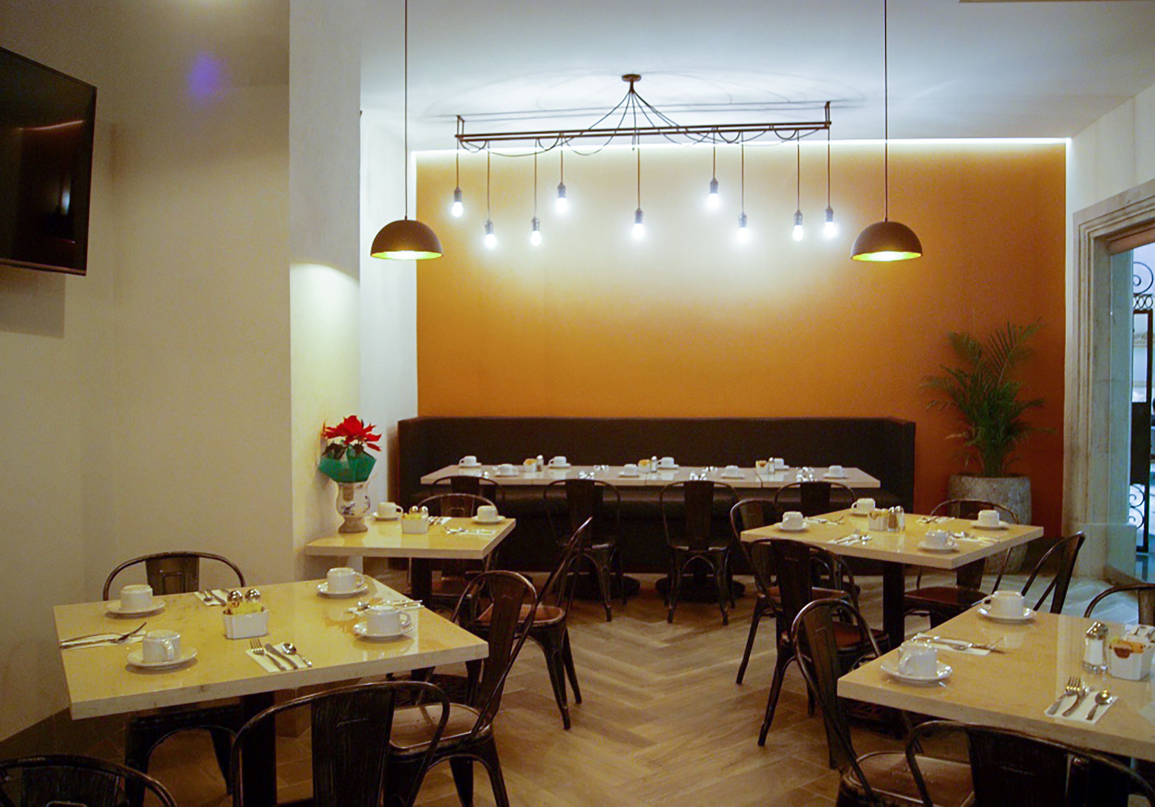 Un restaurante con varias mesas dispuestas para comer, un amplio espacio de estar y un televisor montado en la pared.