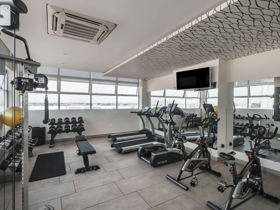 A gym with treadmills, ellipticals, dumbbells, and a stationary bike.