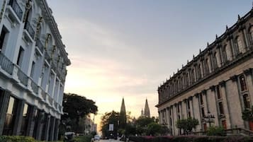 A street view with historic buildings, a church spire, and a clear sky.