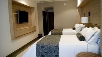 A hotel room with two beds, a flat-screen TV mounted on the wall, a wooden headboard, and a bedside table.