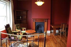 A room with a wooden floor, a fireplace, a dining table, and a chandelier. - The Tasmanian Inn (Hobart)