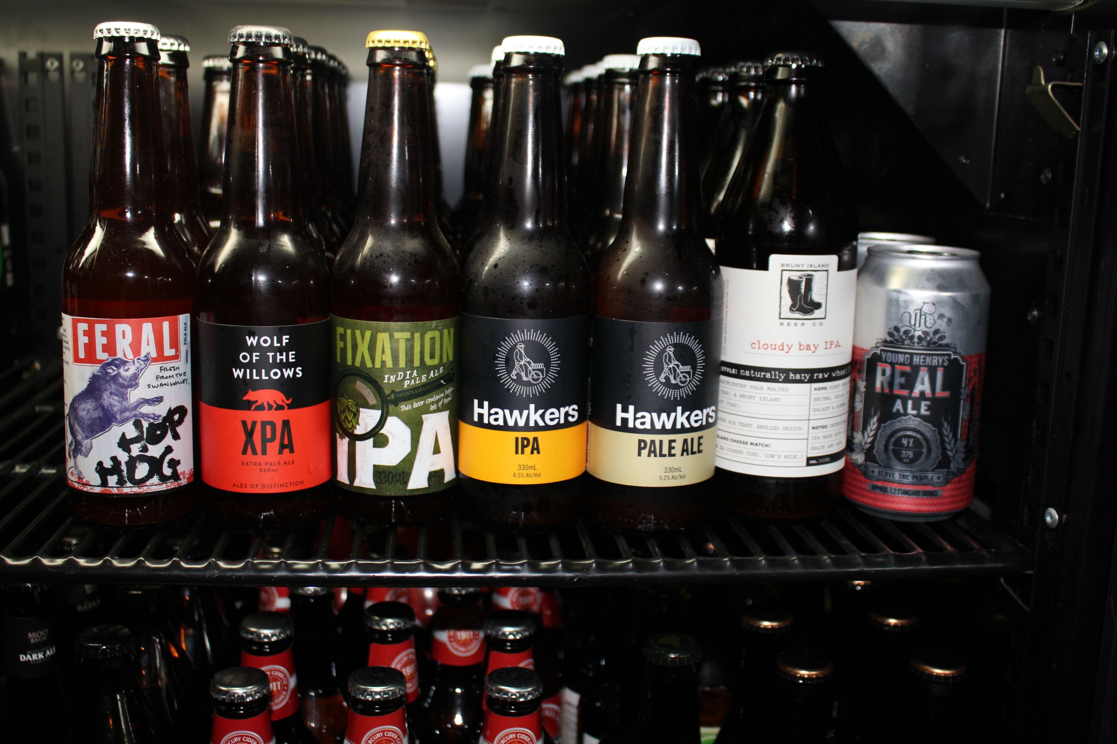 A refrigerated display of various beer bottles and cans.