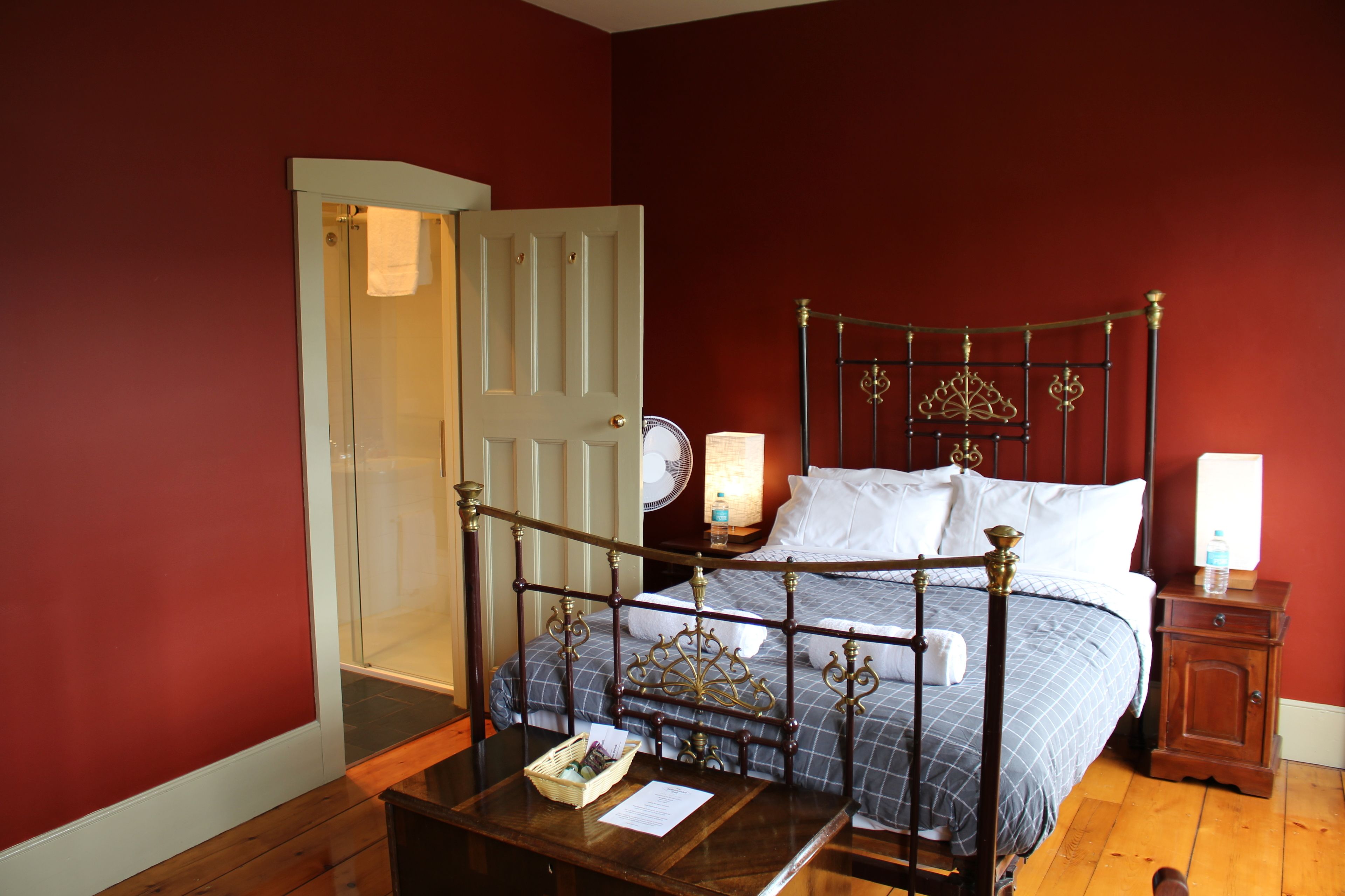 A bedroom with a wooden four-poster bed, a bedside table with a lamp, and a nightstand with a lamp.