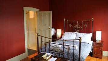 A bedroom with a wooden four-poster bed, a bedside table with a lamp, and a nightstand with a lamp.
