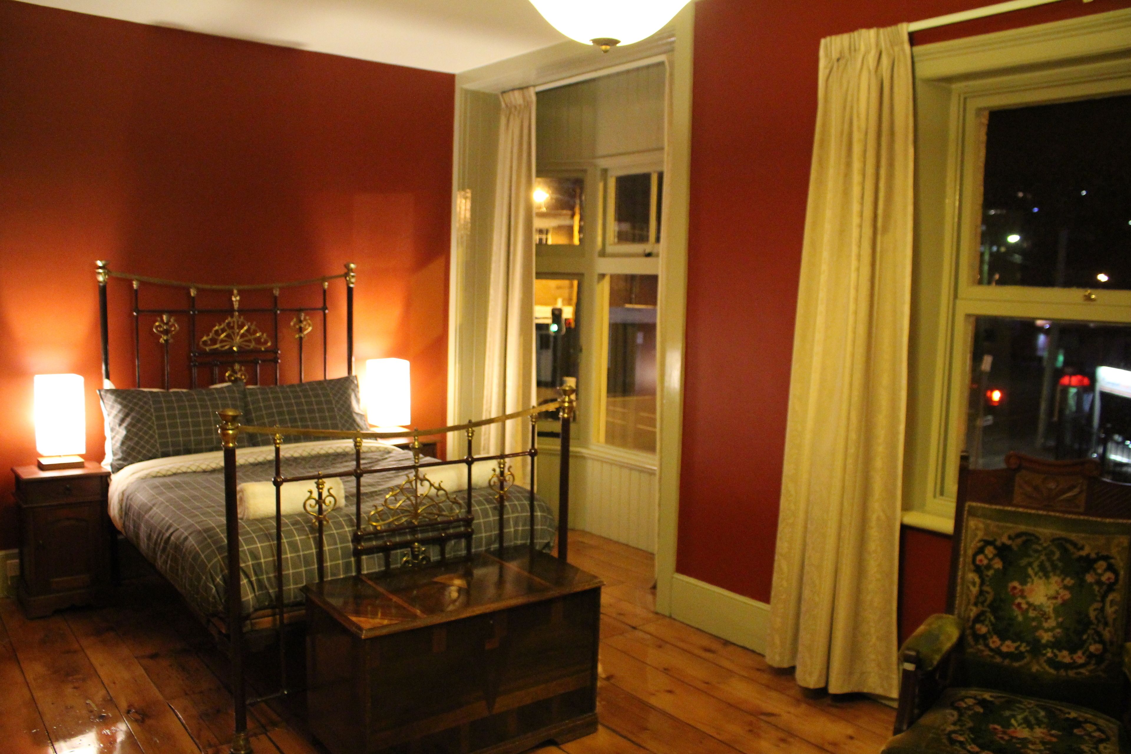 Een slaapkamer met een houten bed, nachtkastjes en een raam met gordijnen.