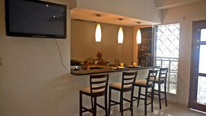 A modern kitchen with a bar area, three pendant lights, and a TV mounted on the wall. - Hostal Santa Martha (Managua)