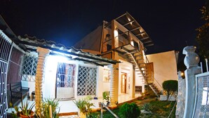 A two-story house with a covered patio, a staircase, and potted plants. - Hostal Santa Martha (Managua)