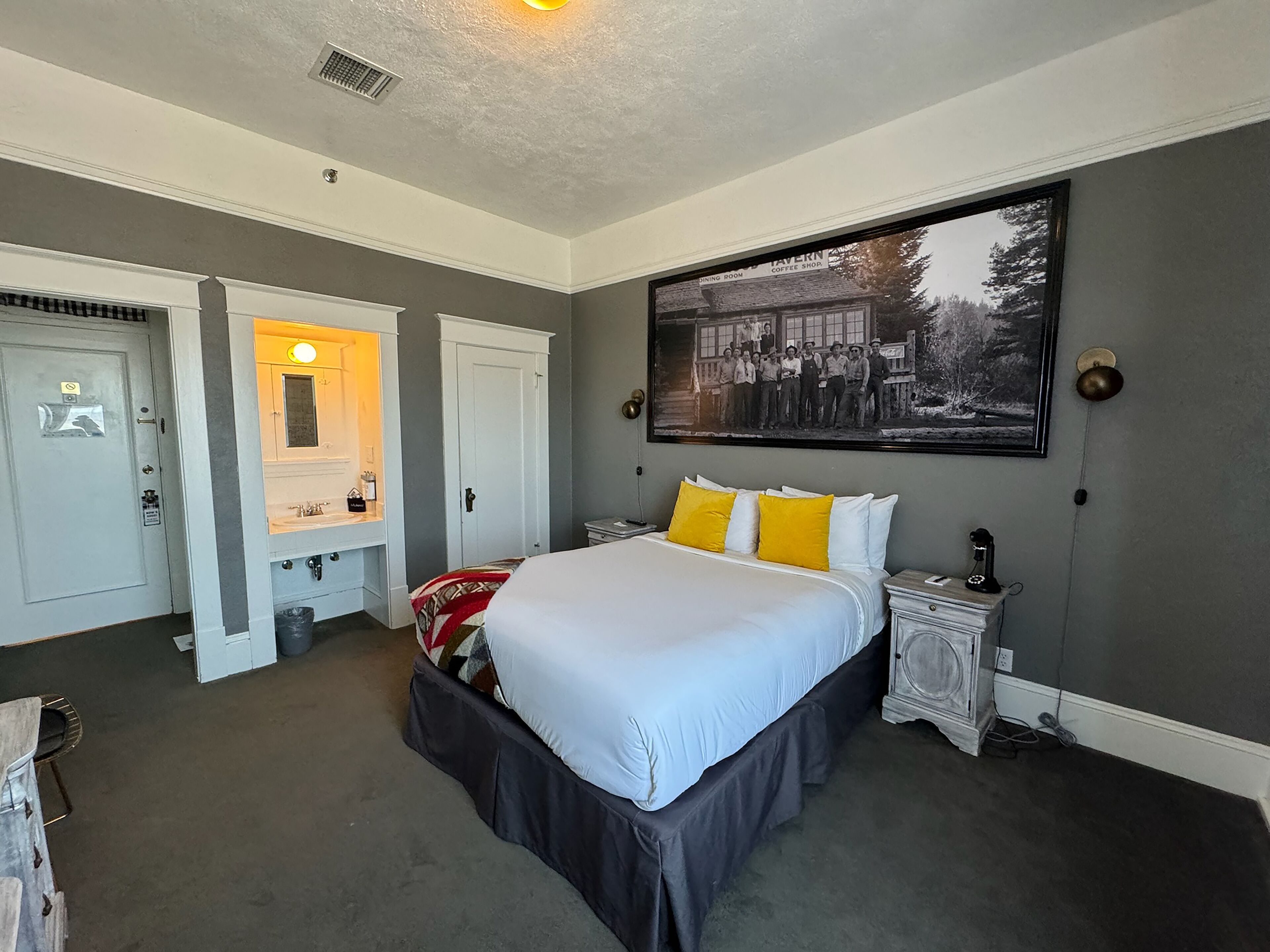Ein Schlafzimmer mit einem großen Bett, einem Schminktisch, einem Frisiertisch und einem gerahmten historischen Foto an der Wand.