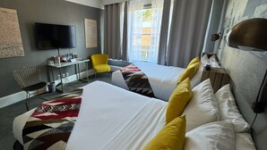 A hotel room with two beds, a desk, a chair, a TV, and a window with curtains. - Hood River Hotel (Hood River)