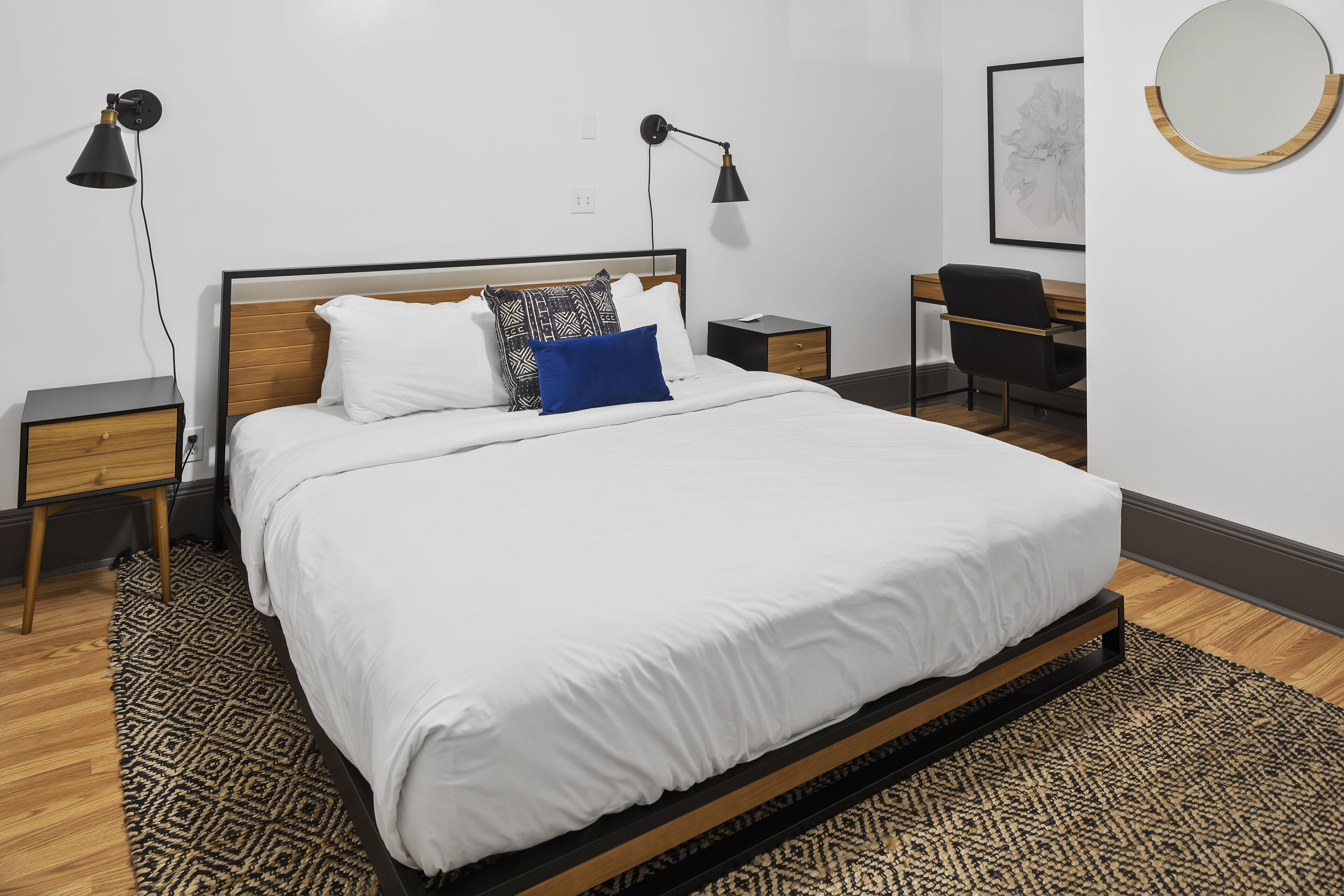 A neatly arranged bedroom with a large bed, two bedside tables, a desk, and a chair.