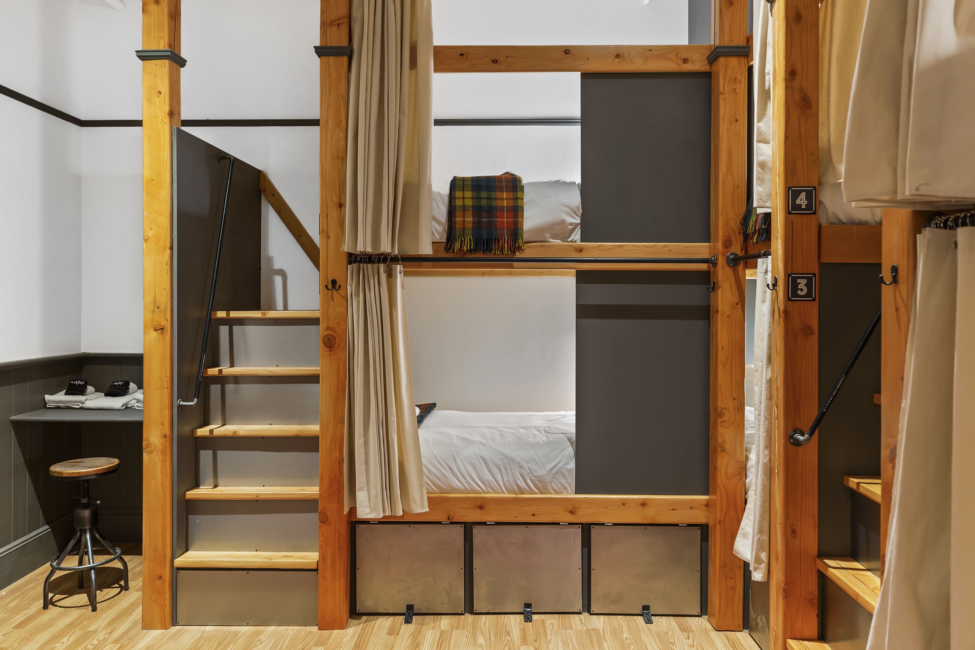 A room with a bunk bed, a desk with a chair, and a staircase.