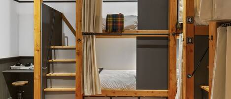A room with a bunk bed, a desk with a chair, and a staircase.