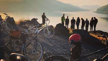 Un gruppo di persone in piedi vicino a un lago, con biciclette e un cane nelle vicinanze.