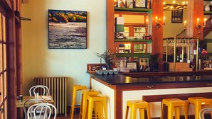 Zona de bar con taburetes, una barra y un cuadro en la pared.