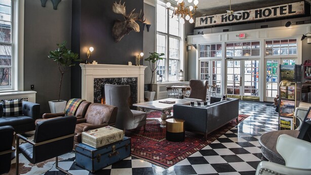 A lobby with a checkered floor, leather sofas, a fireplace, and a mounted moose head. - Hood River Hotel (Hood River)