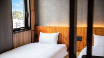 A hotel room with a bed, wooden headboard, and a window with blinds.