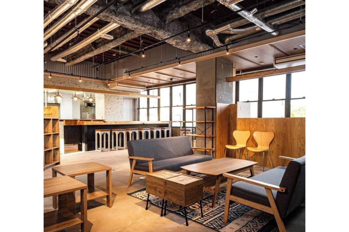 A modern interior with exposed ductwork, wooden furniture, and large windows.