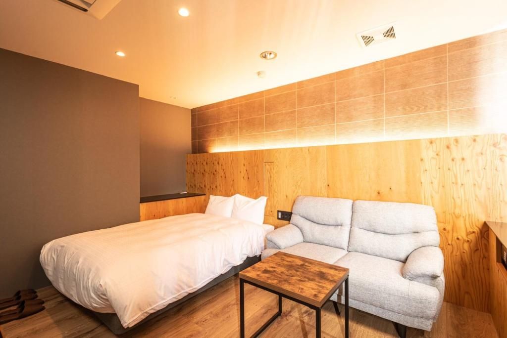 A hotel room with a bed, a sofa, and a small table.