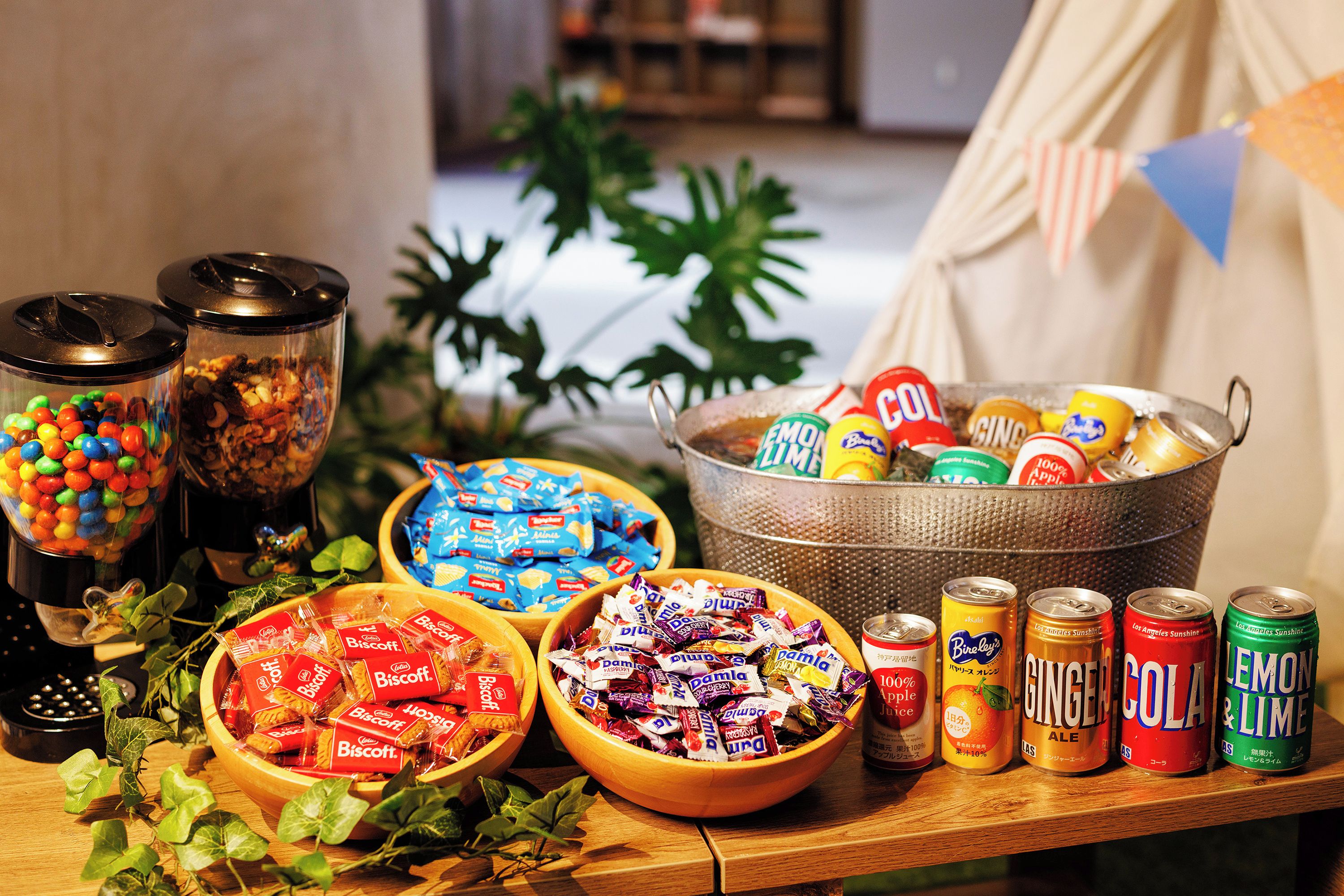 A table with various snacks and drinks, including candy, biscuits, and cans of soda.