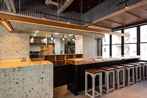 A modern kitchen with a long counter, bar stools, and pendant lighting. - ArC LIFESTYLE SPACE & HOTEL (Mito)