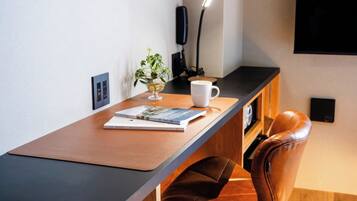 A modern workspace with a leather chair, a wooden desk, a white mug, a book, and a potted plant.