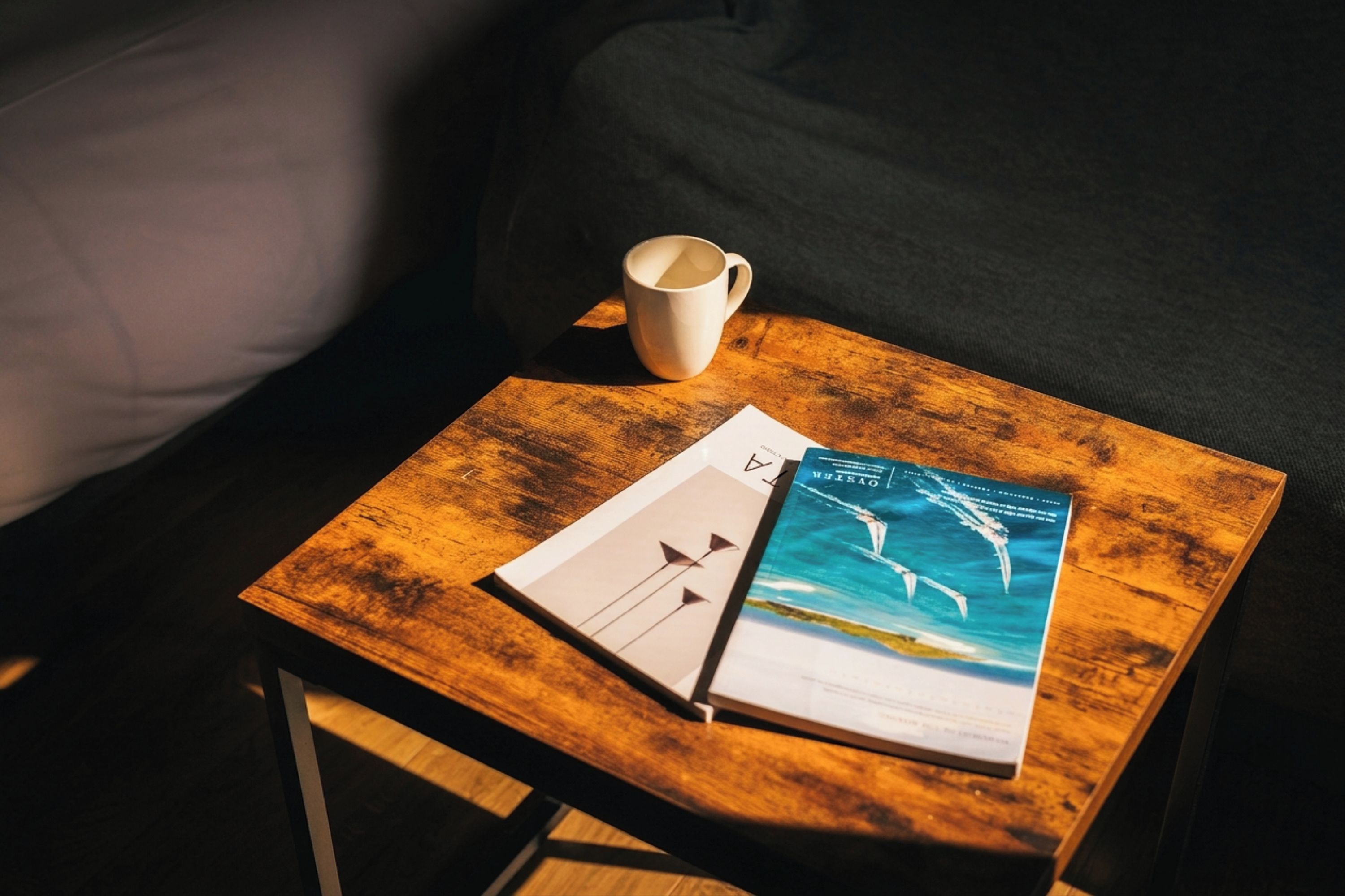 Una mesa de madera con un libro y una taza, colocada sobre un sofá.