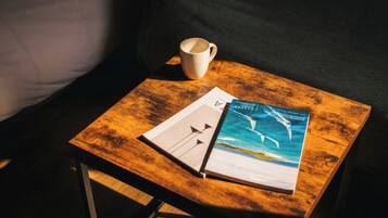 Una mesa de madera con un libro y una taza, colocada sobre un sofá.