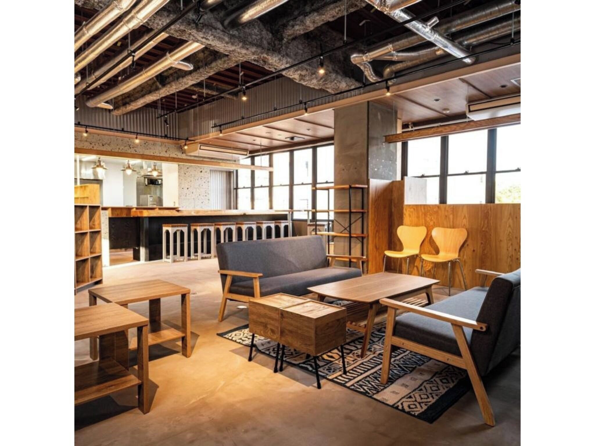 A modern interior with exposed ductwork, wooden furniture, and large windows.