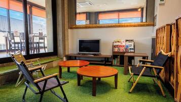 A room with a television, two round tables, and three chairs.