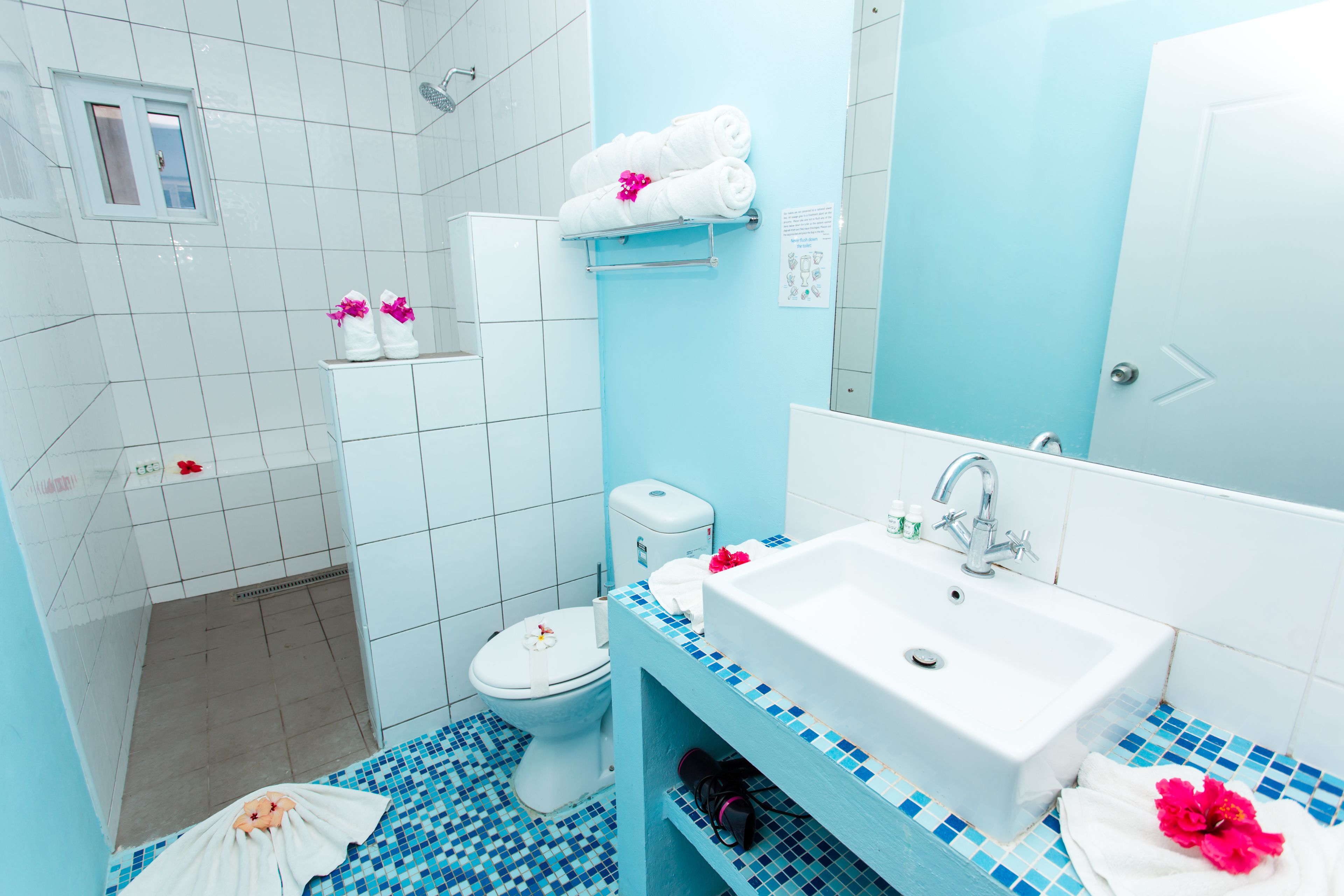 A bathroom with a white toilet, a sink with a mirror, and a shower area.