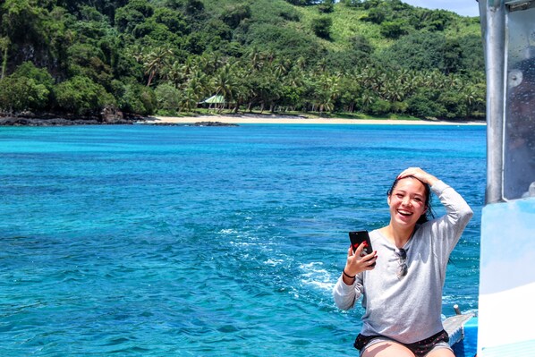 Una persona en un bote con vista a una playa y un bosque al fondo.