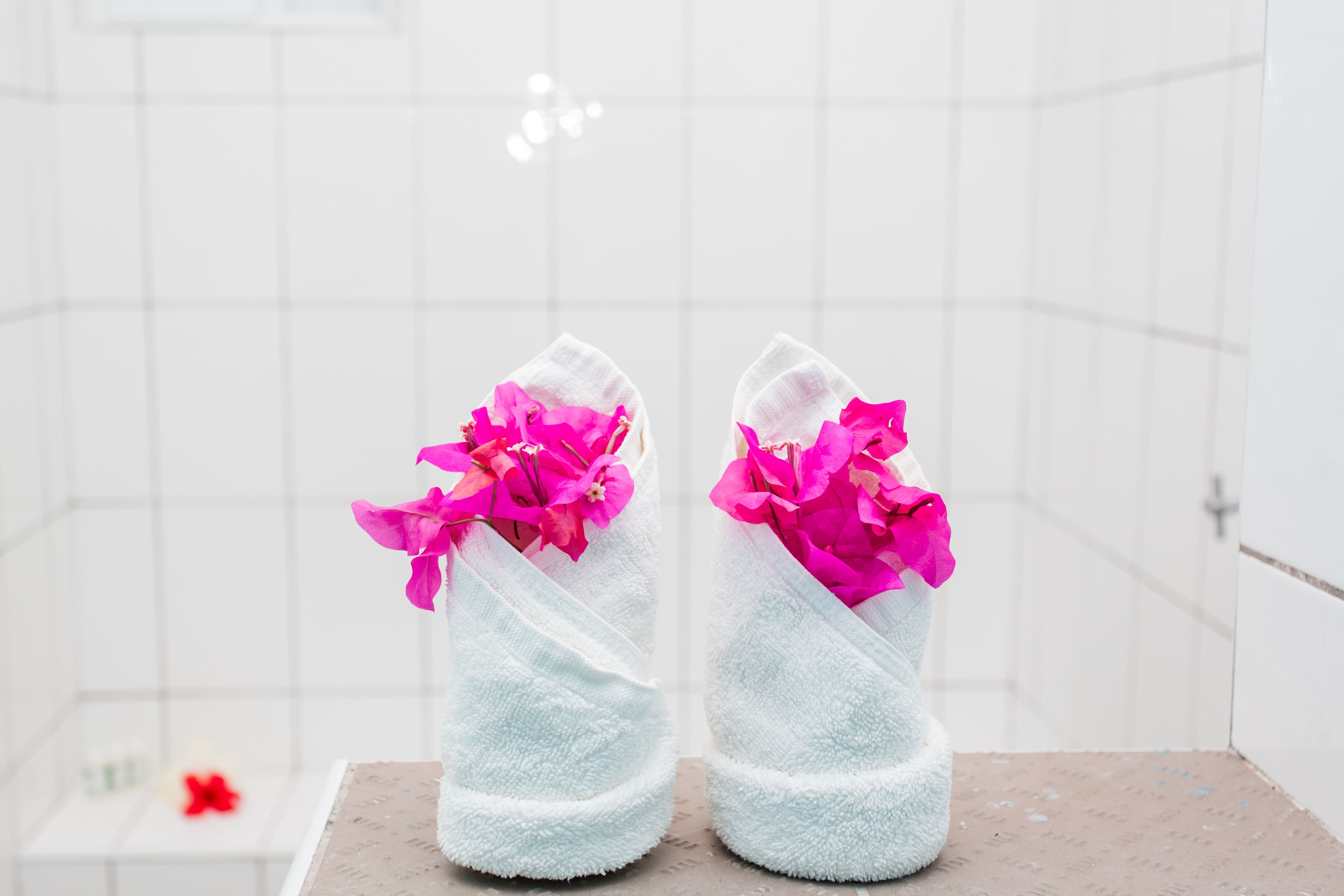 Ett par vita tofflor med rosa blommor på ett klinkergolv.