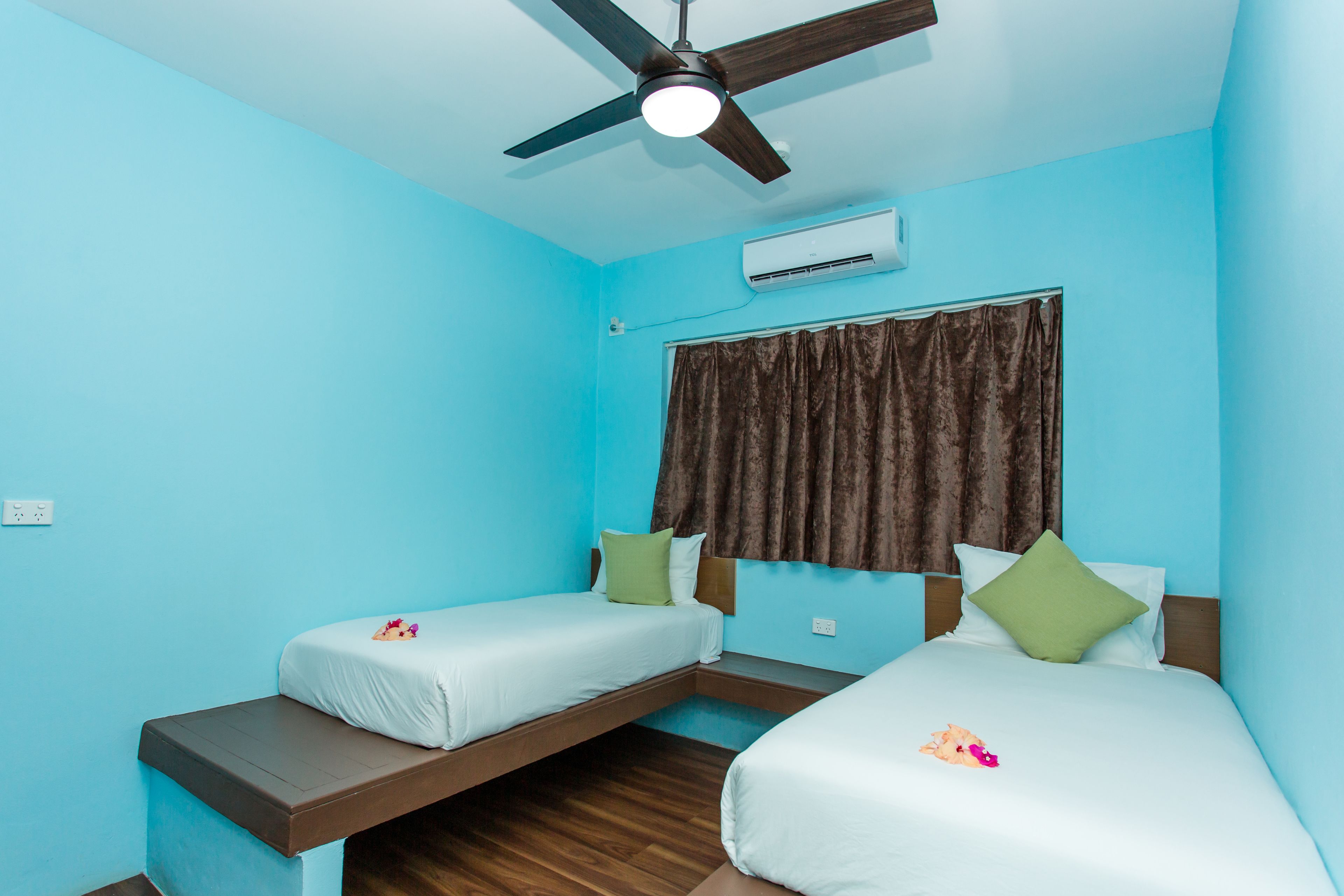 Ein Zimmer mit zwei Betten, einem Deckenventilator und einer Klimaanlage.