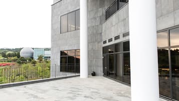 Een modern gebouw met grote ramen, een binnenplaats en een bolvormige structuur op de achtergrond.