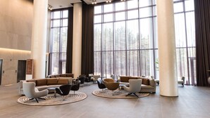 A spacious lobby with large windows, modern furniture, and a high ceiling. - Hotel Nanta Jeju (Jeju City)