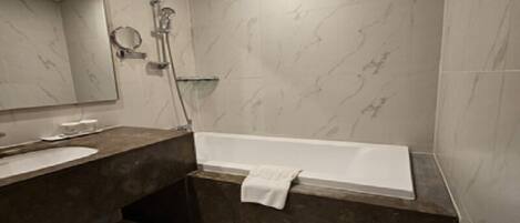 A modern bathroom with a marble vanity, a large mirror, a bathtub, and a shower area.