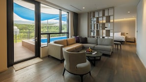 A modern living room with a large sliding glass door leading to a balcony, a sectional sofa, a small round table, and a built-in shelving unit. - Hotel Nanta Jeju (Jeju City)