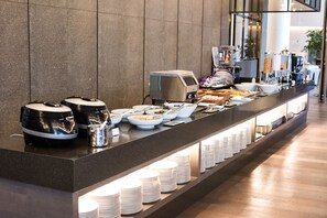 Montaje de bufé con diversas opciones de comida y una estación de café.