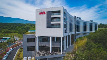 Een modern hotel met een opvallend 'HOTEL NANTA' bord, meerdere verdiepingen en een terras op het dak met buiten zitplaatsen.